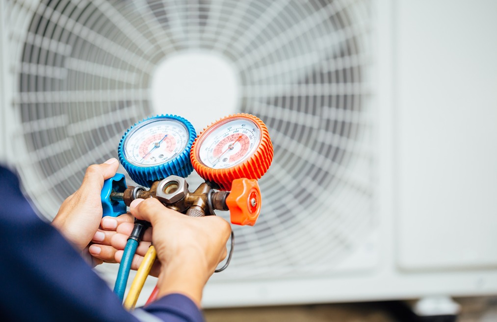 Technician checking refrigerant gauges during commercial HVAC service and maintenance