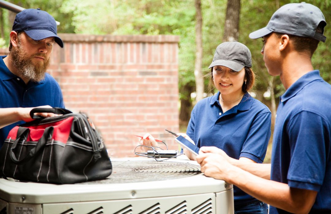 HVAC service team discussing work beside a residential outdoor unit