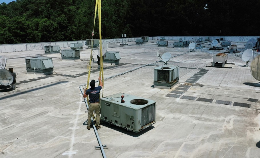 Technician servicing rooftop commercial HVAC equipment on a large building