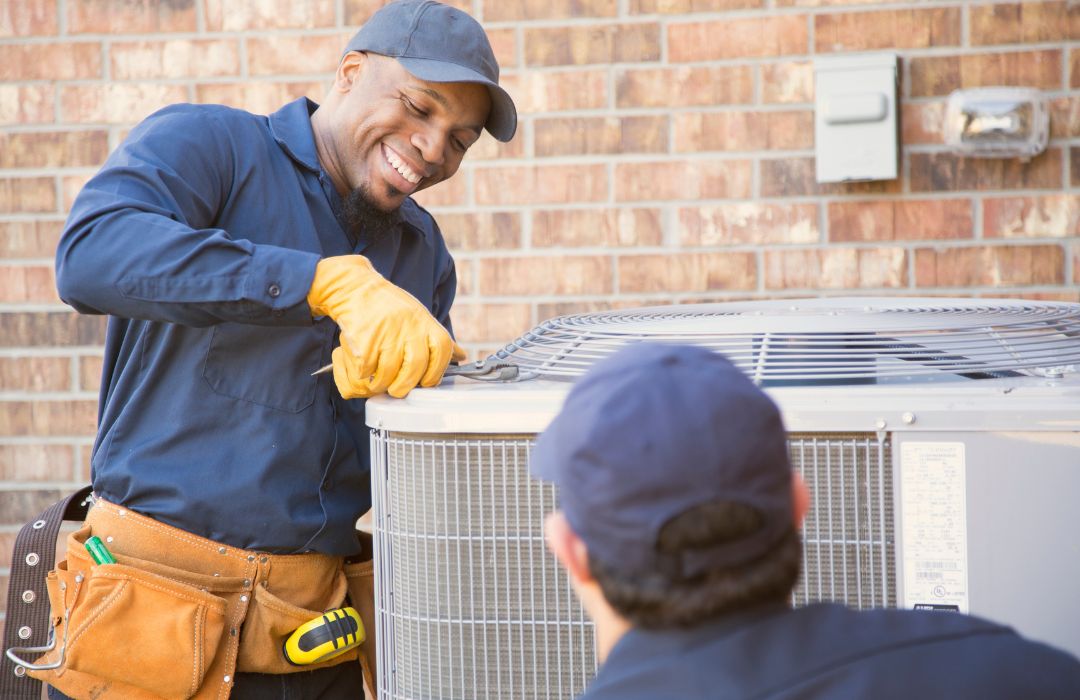 HVAC technician servicing a residential outdoor air conditioning unit during maintenance