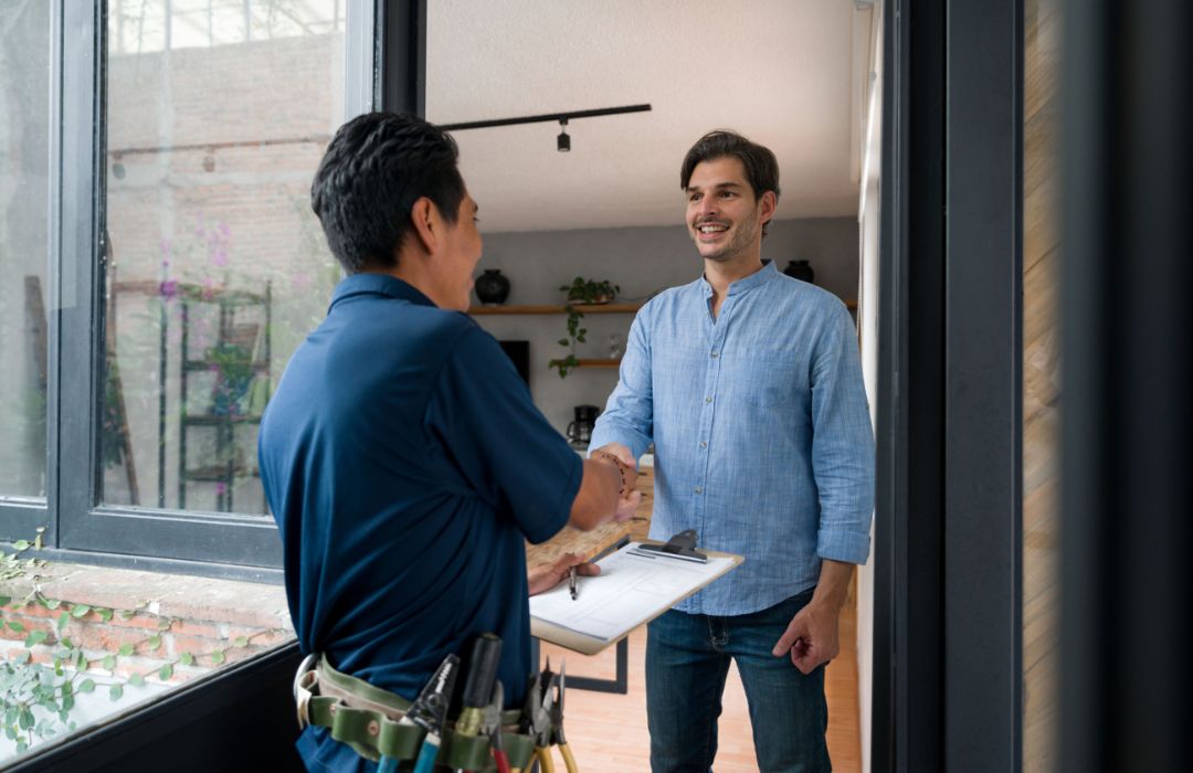 HVAC technician greeting homeowner at the front door with clipboard before service visit